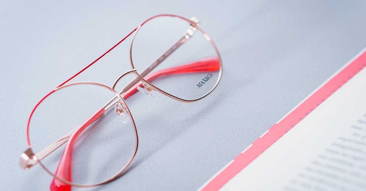 close up of stylish red rimmed eyeglasses on a desk next to an open document